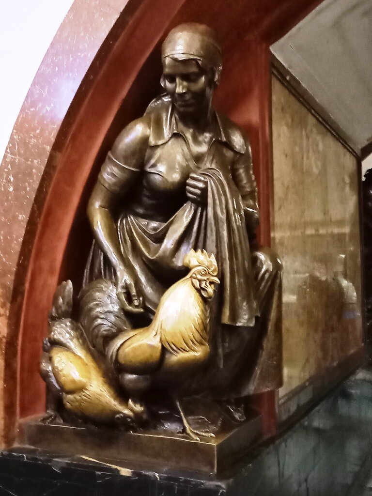 Вообще-то это скульптура птичницы с курицей и петухом в шестой арке станции метро. 