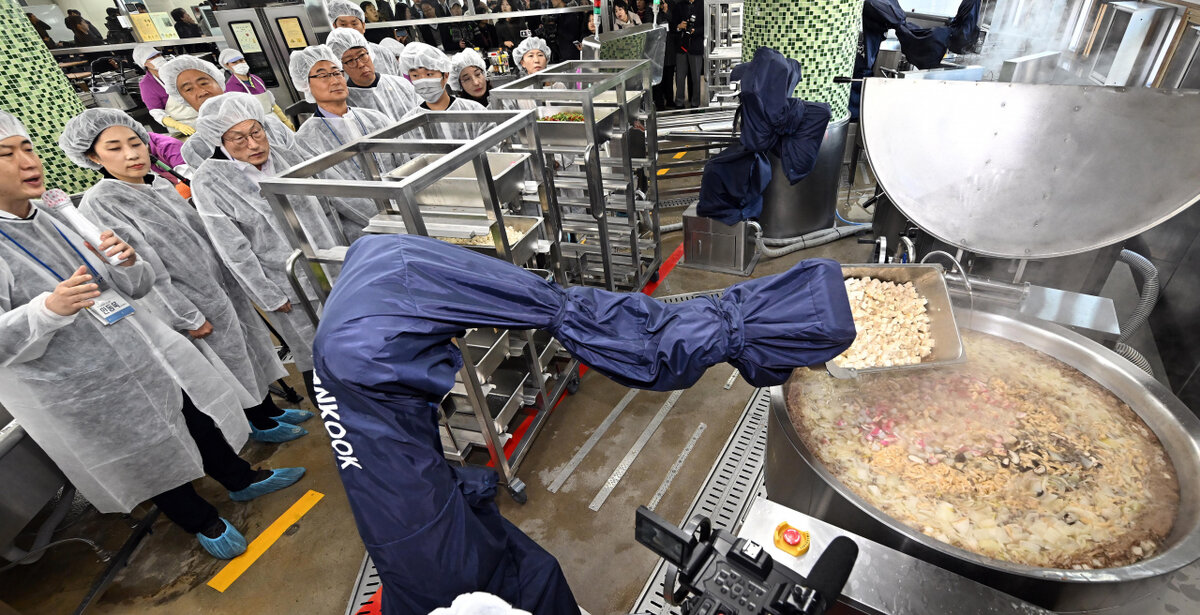 Робот,  предназначенный для выполнения кулинарных задач, готовит школьную еду  для 730 человек, включая учеников и сотрудников школы, в средней школе  Сунгок в Сонбук-гу на севере Сеула (Объединенный пресс-корпус)
