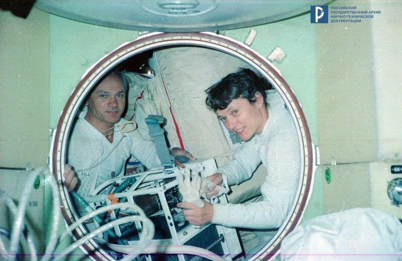 В.А. Джанибеков и С.Е. Савицкая готовят оборудование для проведения эксперимента с использованием универсального ручного инструмента (УРИ) во время выхода в открытый космос с борта орбитальной станции «Салют-7». Июль 1984 г. РГАНТД. Арх. № 1-3974 цв.