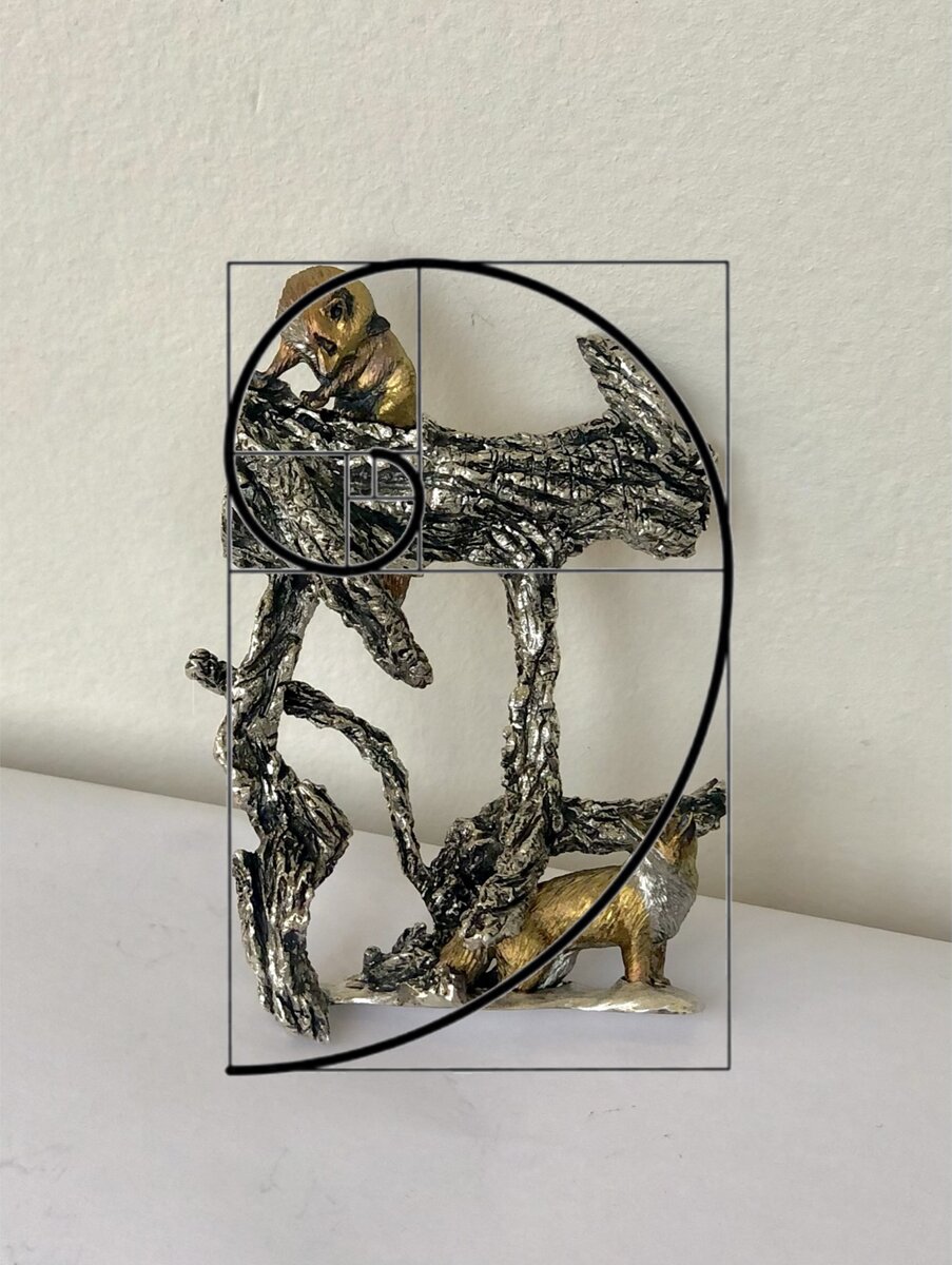 Верхняя лиса полностью вписана в свой квадрат; торчащая вверх ветка справа идет по изгибу линии; верхняя ветка+верхняя лиса расположены в пределах верхнего прямоугольника; детали в большом квадрате, в противовес, более воздушные, там меньше металла; глаз нижней лисы лежит на линии, острый конец ветки слева стремится вниз к линии.