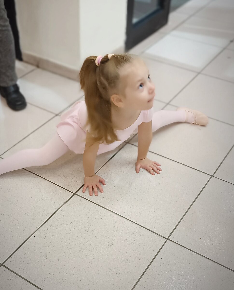 тренерует растяжку в холле перед занятиями