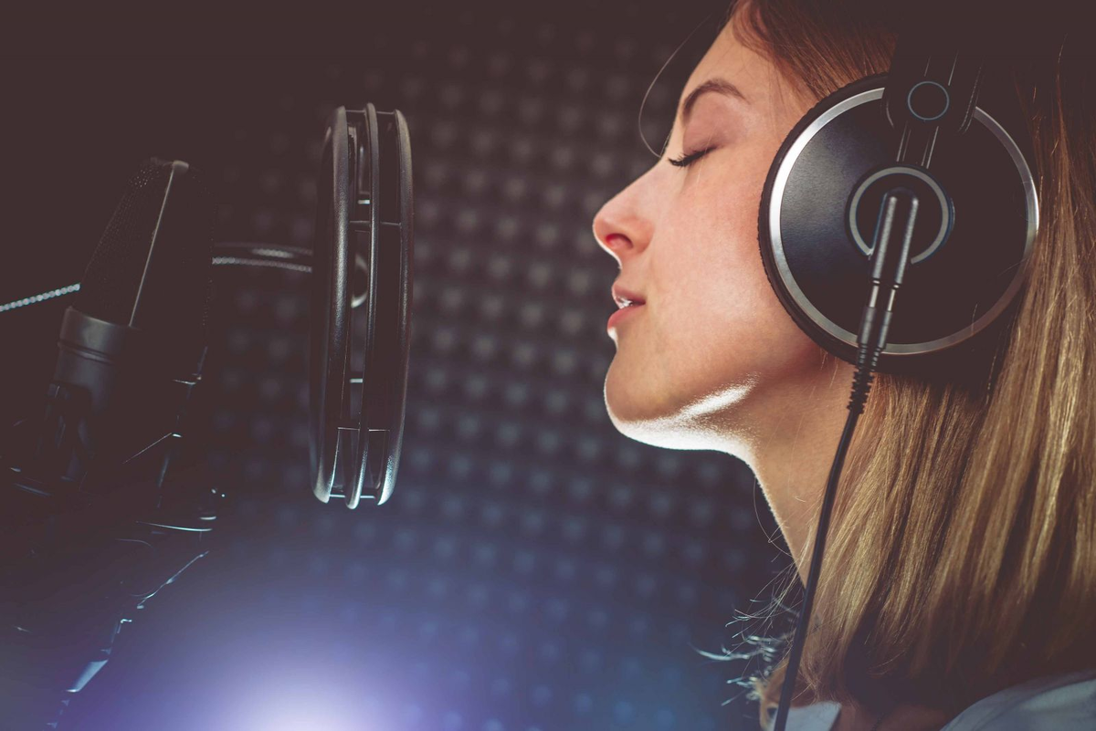 Петь песни в наушниках. Девушка с микрофоном в студии. Девушка поет. Девушка поет в студии. Девушка в студии звукозаписи.