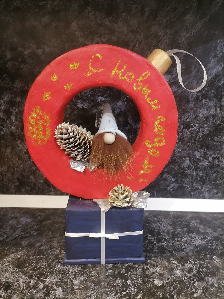 Новогодняя игрушка с гномом на коробке с подарком.