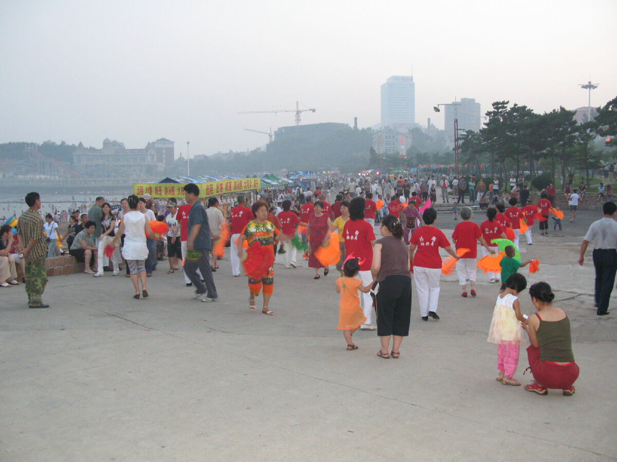 Пожилые китайцы танцуют на набережной.