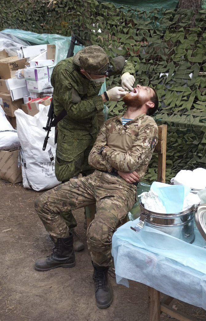 Медик-стоматолог, не расстающийся с автоматом, в двух километрах от передовой оказывает бойцу неотложную помощь