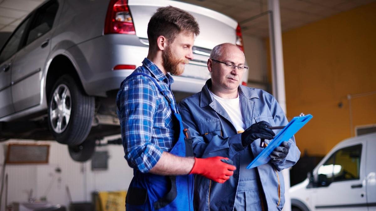    Два техника на фоне поднятой машины:Freepik/gpointstudio