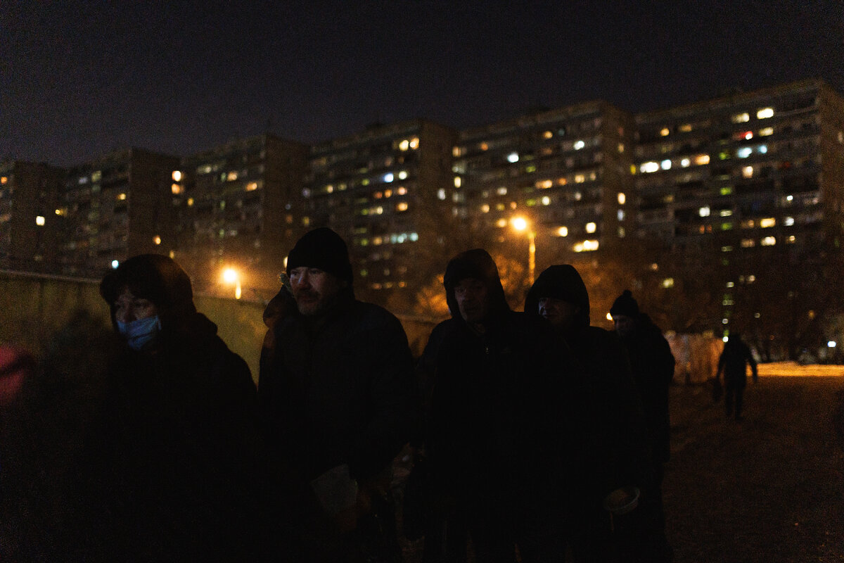 Бездомные люди на стоянке Ночного автобуса в ожидании горячего ужина