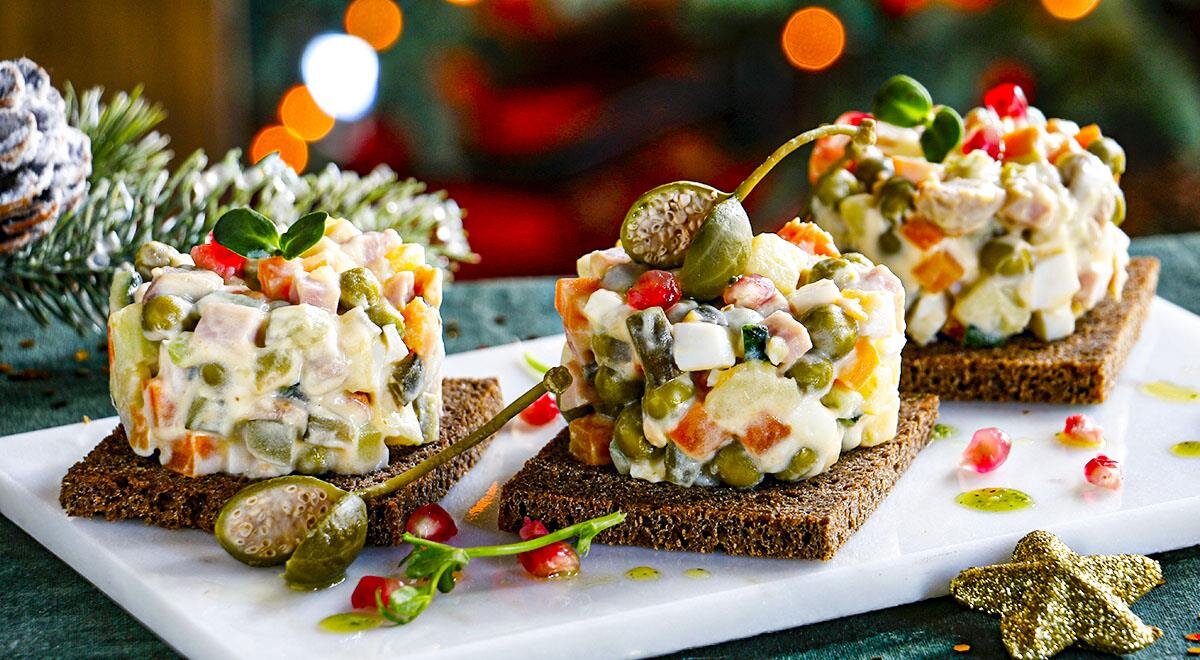 Оливье с уткой на бородинском хлебе – необычная вариация рецепта классического новогоднего салата и способа его сервировки. Традиционные мясо или вареную колбасу мы предлагаем заменить сочетанием обжаренного утиного филе и сырокопченого окорока, которые придадут салату совершенно особенный вкус. А споров о том, добавлять в оливье яблоко или огурец, а если огурец – свежий или маринованный, и вовсе предлагаем не вести и добавить все три ингредиента. Подайте салат порционными шайбами на ломтике бородинского хлеба без корочки индивидуально каждому гостю – и принимайте заслуженные комплименты!