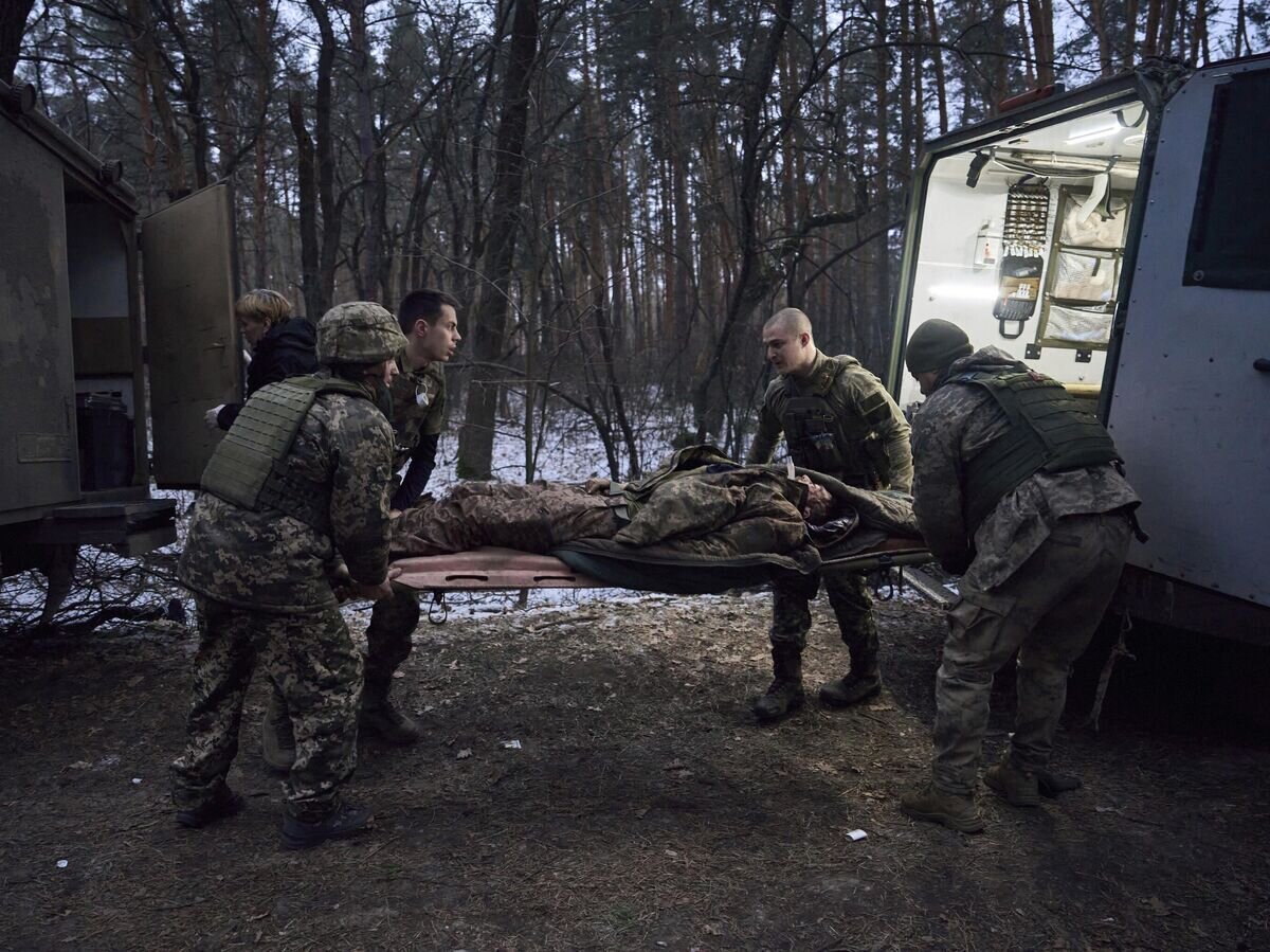    Медики помогают тяжело раненому украинскому солдату© AP Photo / LIBKOS