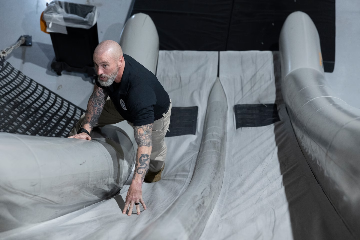 Майкл Лафранс, воздушный маршал, демонстрирует использование самолетной горки в учебном центре TSA в Атлантик-Сити.