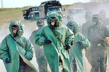 Бойцы в костюмах общевойскового защитного комплекта (ОЗК) и противогазах движутся по заражённой местности