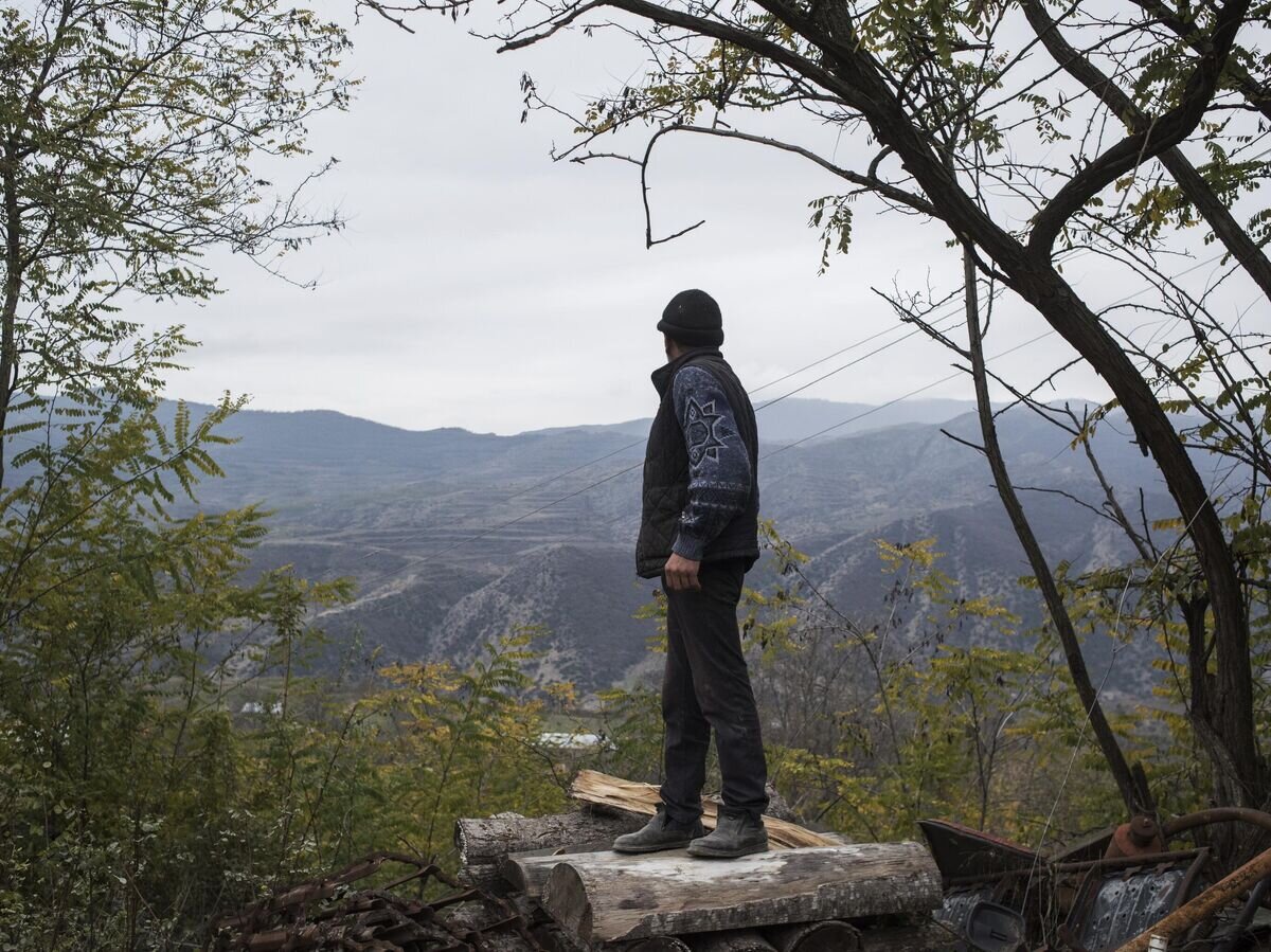    Мужчина смотрит на горы возле своего дома в поселке Карегах© РИА Новости / Валерий Мельников
