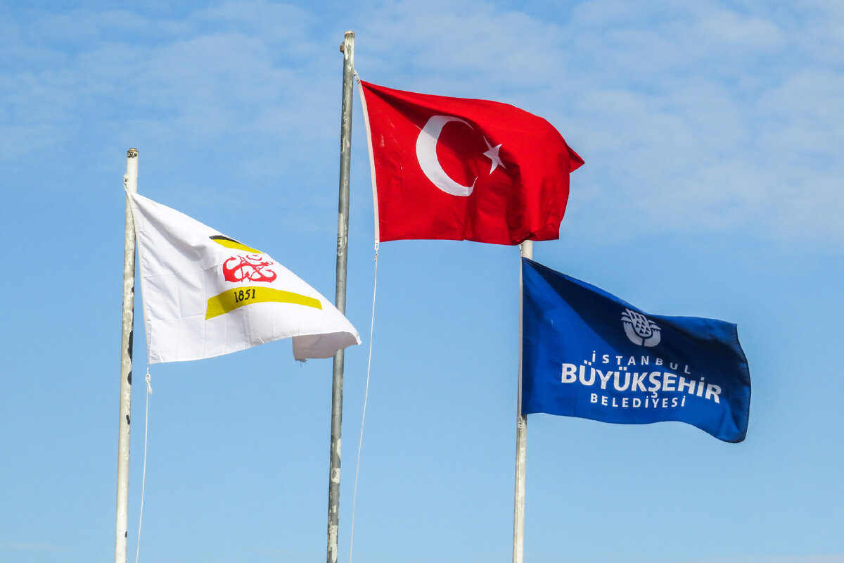 Слева флаг с цветами и значком паромной компании Şehir Hatları