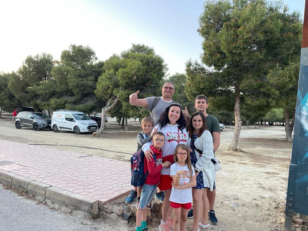 На заднем фоне этой весёлой кампании расположена большая парковка