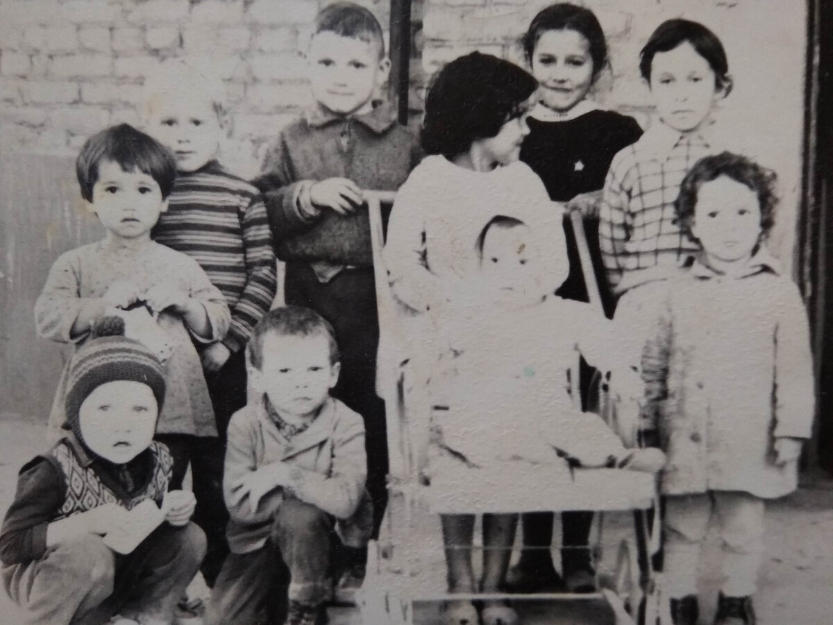 Я стою рядышком с коляской, справа, в первом ряду. Маленькая, кудрявая.