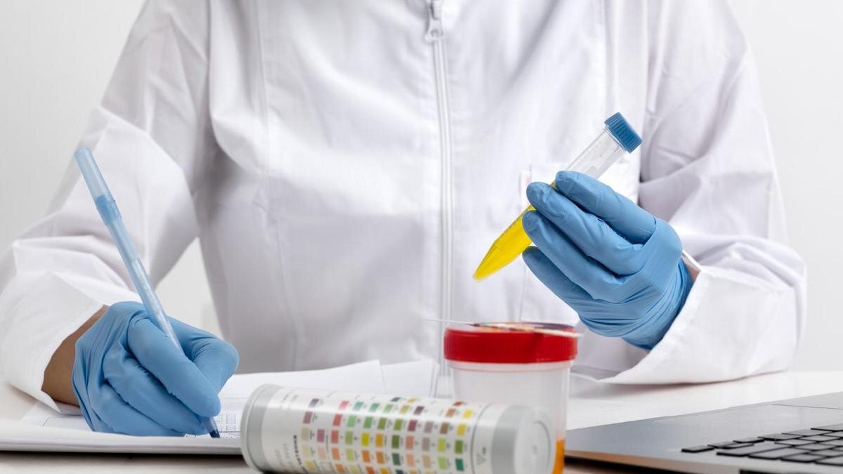    Лаборант держит пробирку с желтой жидкостью:Freepik