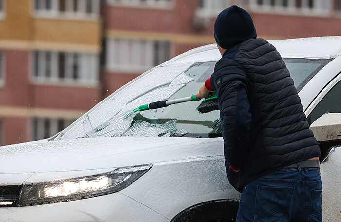    Мужчина чистит машину ото льда. Сильный ветер с порывами до 18 метров в секунду и ледяной дождь стали причиной перебоев в подаче электроэнергии в трех районах Ростовской области.Эрик Романенко/ТАСС