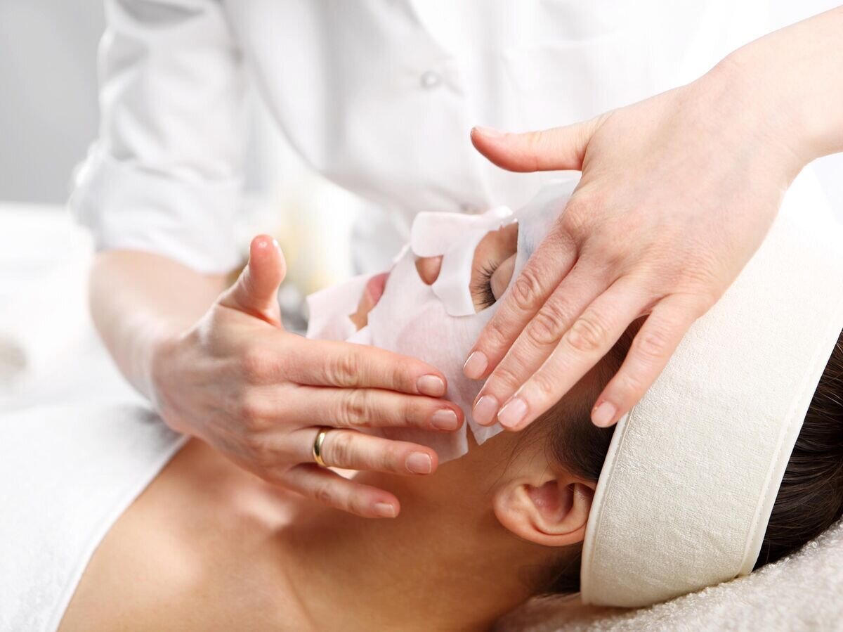    Косметолог наносит девушке маску на лицо© iStock.com / robertprzybysz