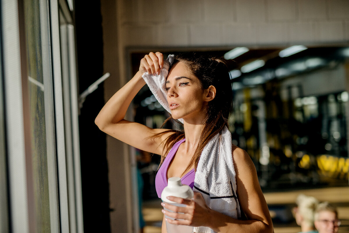 Сильно потею во время тренировки. Девушка вытирает пот. Вытирает пот во время тренировки. Девушка потеет. Вспотевшая девушка на работе.