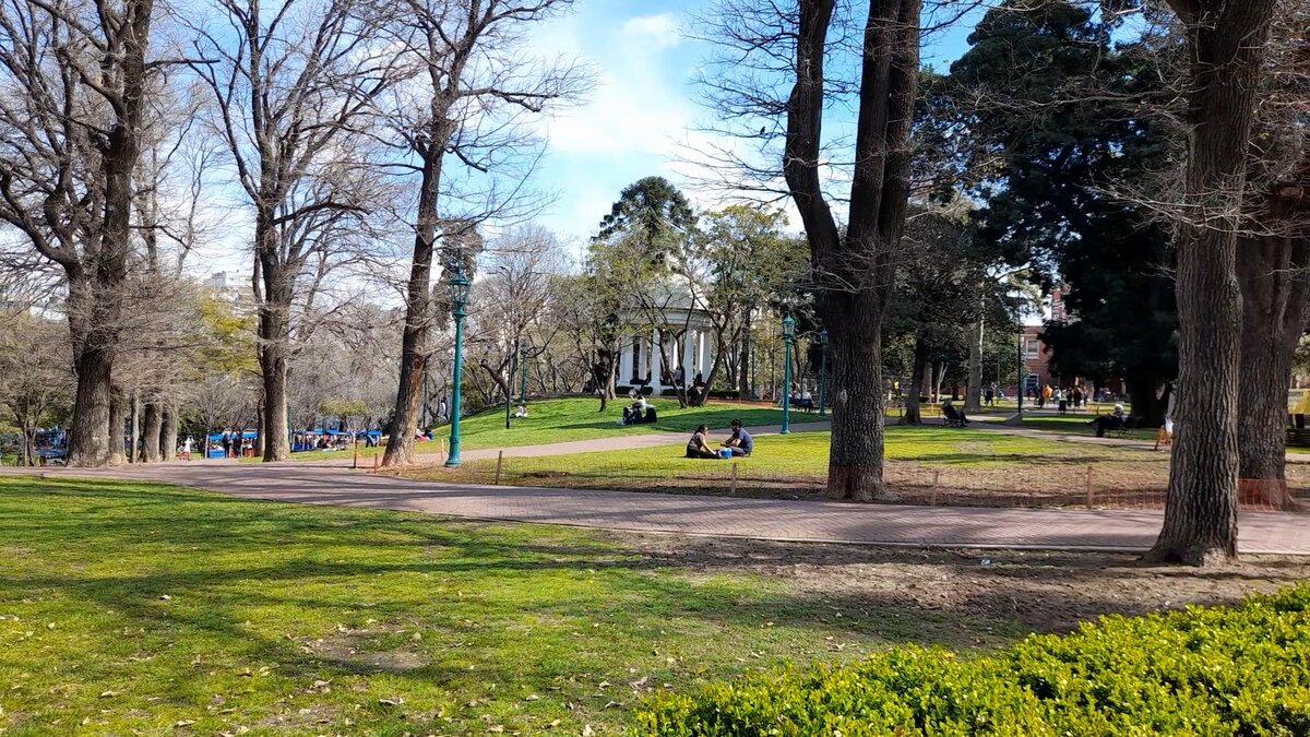 За деревьями виден храм в древнегреческом стиле.