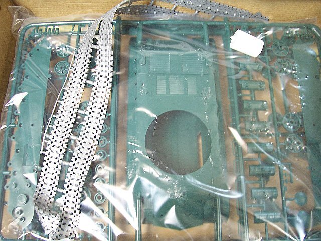 Набор деталей для создания модели тяжёлого советского танка ИС-3. Поверх пакета с деталями видны баночка с клеем и две виниловые ленты гусениц.