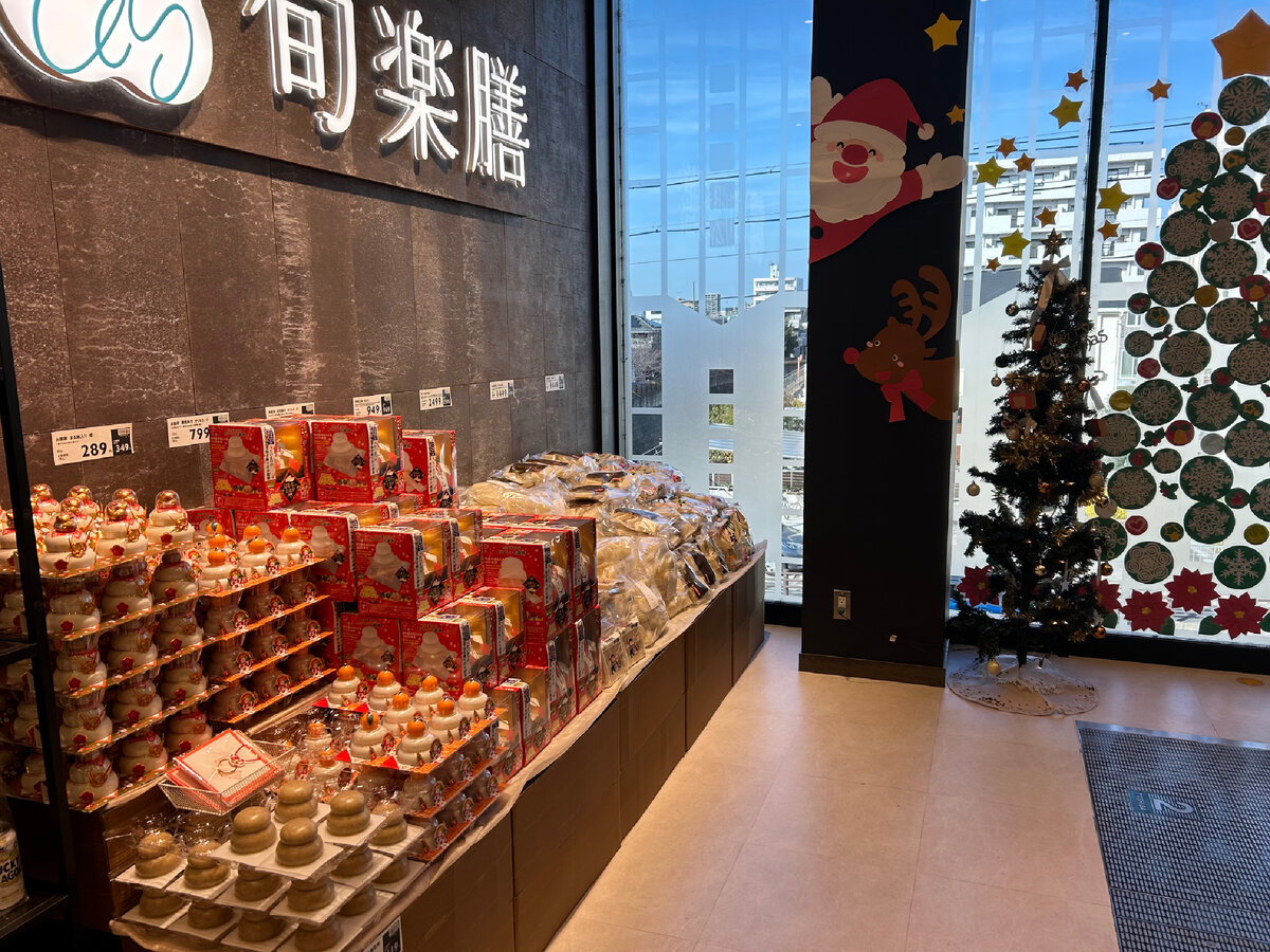 Так в японском магазине традиционное японское новогоднее угощение продаётся на фоне украшения в европейском стиле.