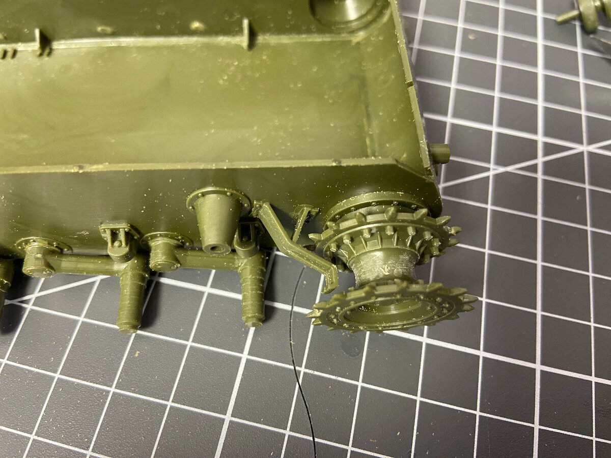 Цапфы балансиров (в обиходе - оси) перед покраской следует закрыть малярным скотчем. Иначе будет сложно приклеивать колёса поверх краски. И обратите внимание на размер приводной звёздочки: уверены, что сможете покрасить за нею крышку бортового редуктора? А ведь его будет точно видно, когда зритель захочет рассмотреть модель поближе.  На фото - фрагмент корпуса сборной модели танка КВ-2 в масштабе 1/35 от "Звезды".