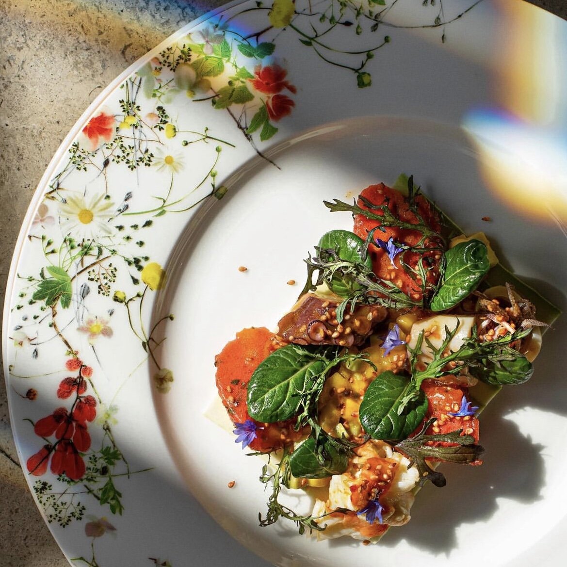 Веточки зелени и цветочки, которыми повар украшает закуску, словно продолжаются в узоре на бортике тарелки