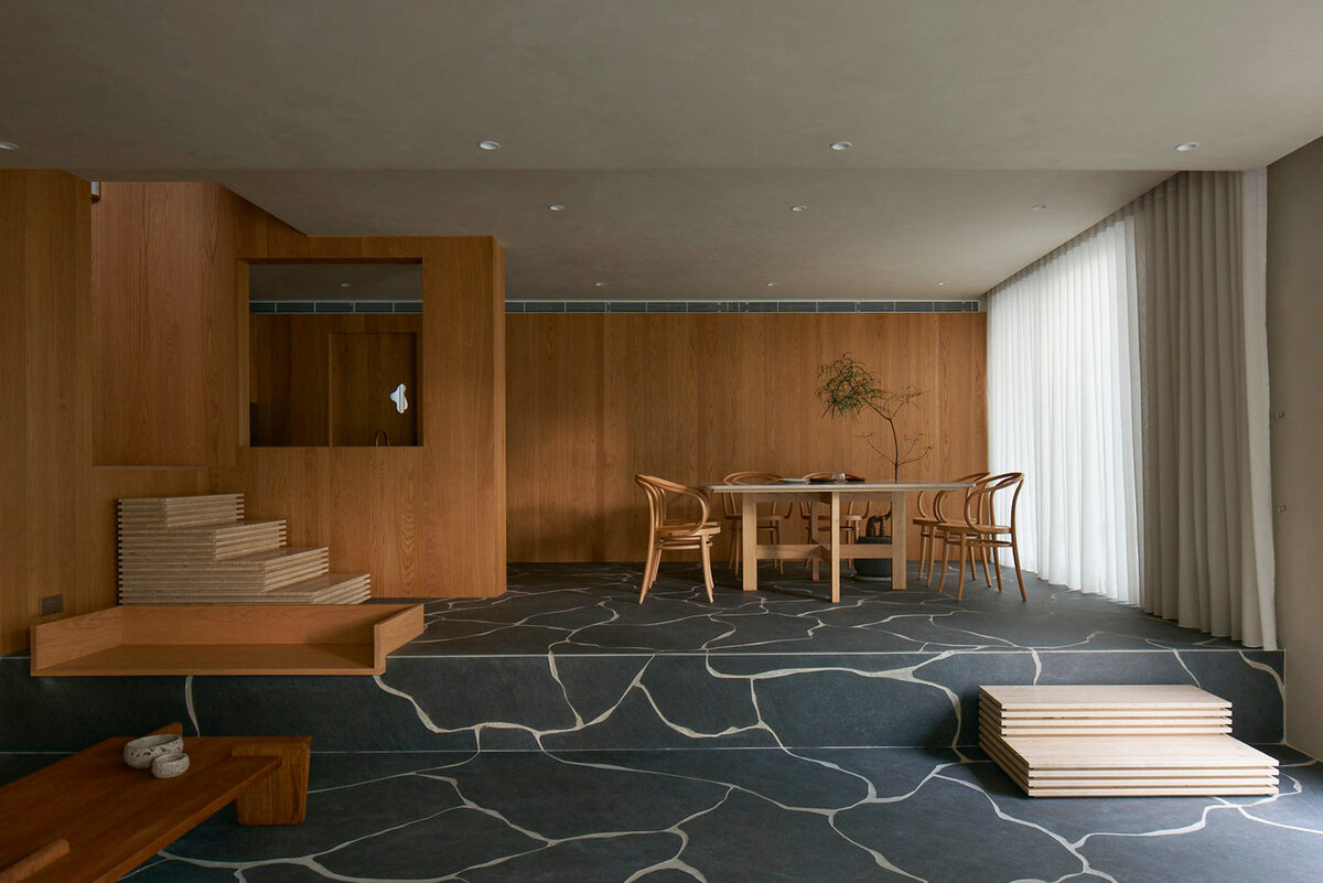 В этом сингапурском доме по проекту бюро L Architects гостиная и столовая расположены на разных уровнях, переход между ними обозначен акцентными травертиновыми ступенями и деревянной скамьей, встроенной в приподнятый участок. Обеденный стол из шлифованного известняка выполнен на заказ, один из его углов иссечен, чтобы освободить место для растения в кадке и таким образом подчеркнуть близость интерьера к природе. Фото: Jovian Lim.