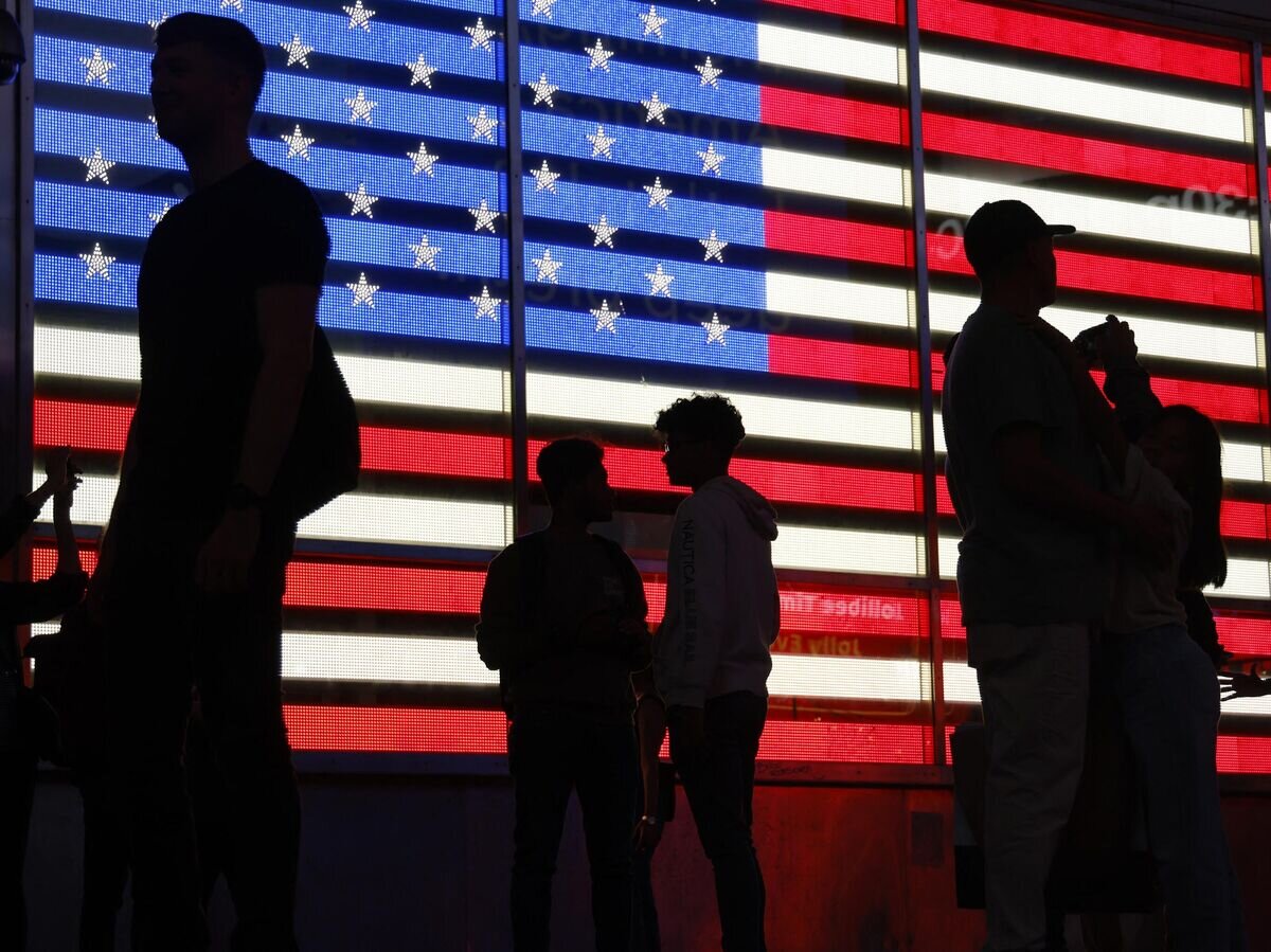    Люди стоят перед флагом США© AFP 2023 / Ludovic Marin