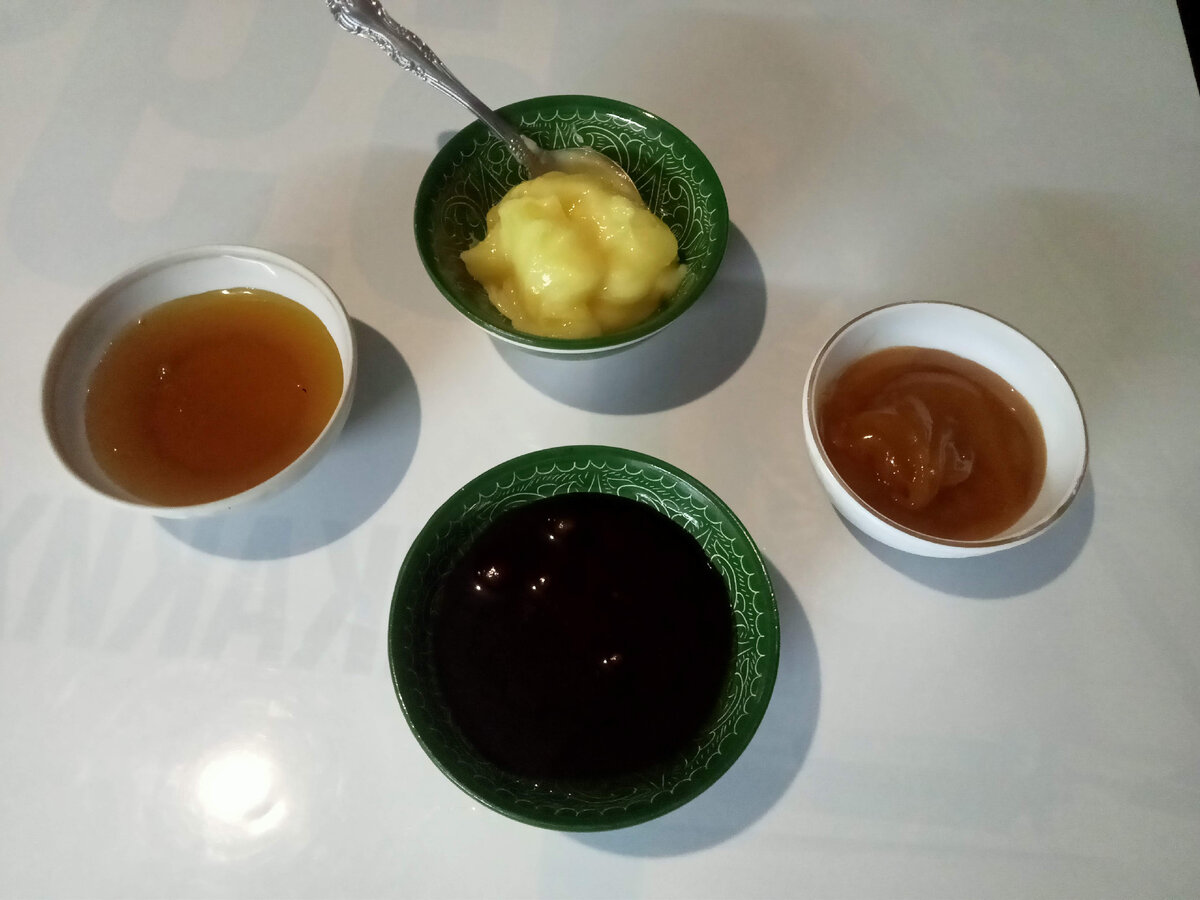 слева прозрачный местный мед, с ложечкой липовый, в маленькой вазочке алтайский, темный гречишный.