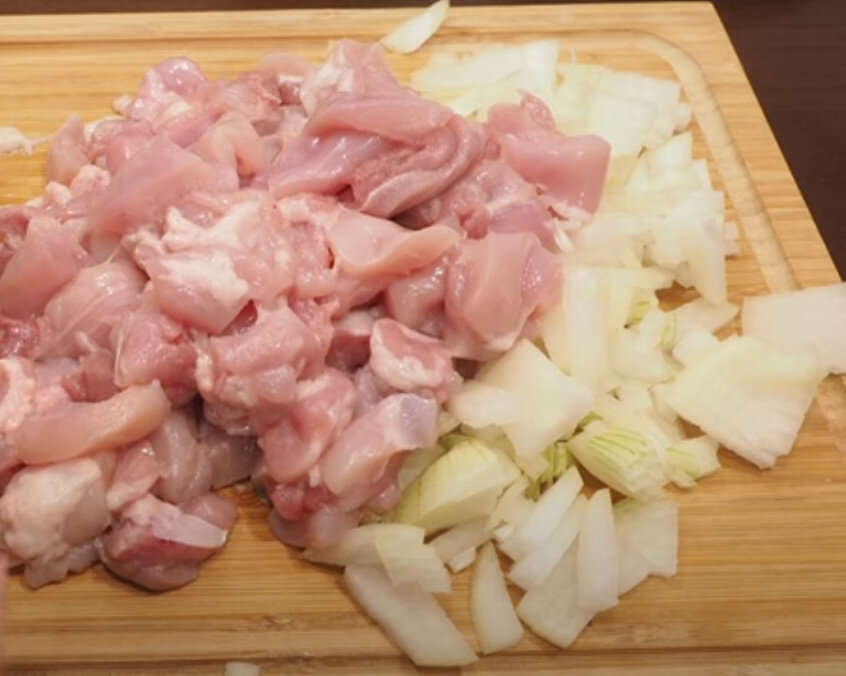 Нарезанные лук и куриные бёдрышки