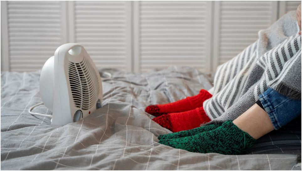 ** Люди греются с помощью обогревателя