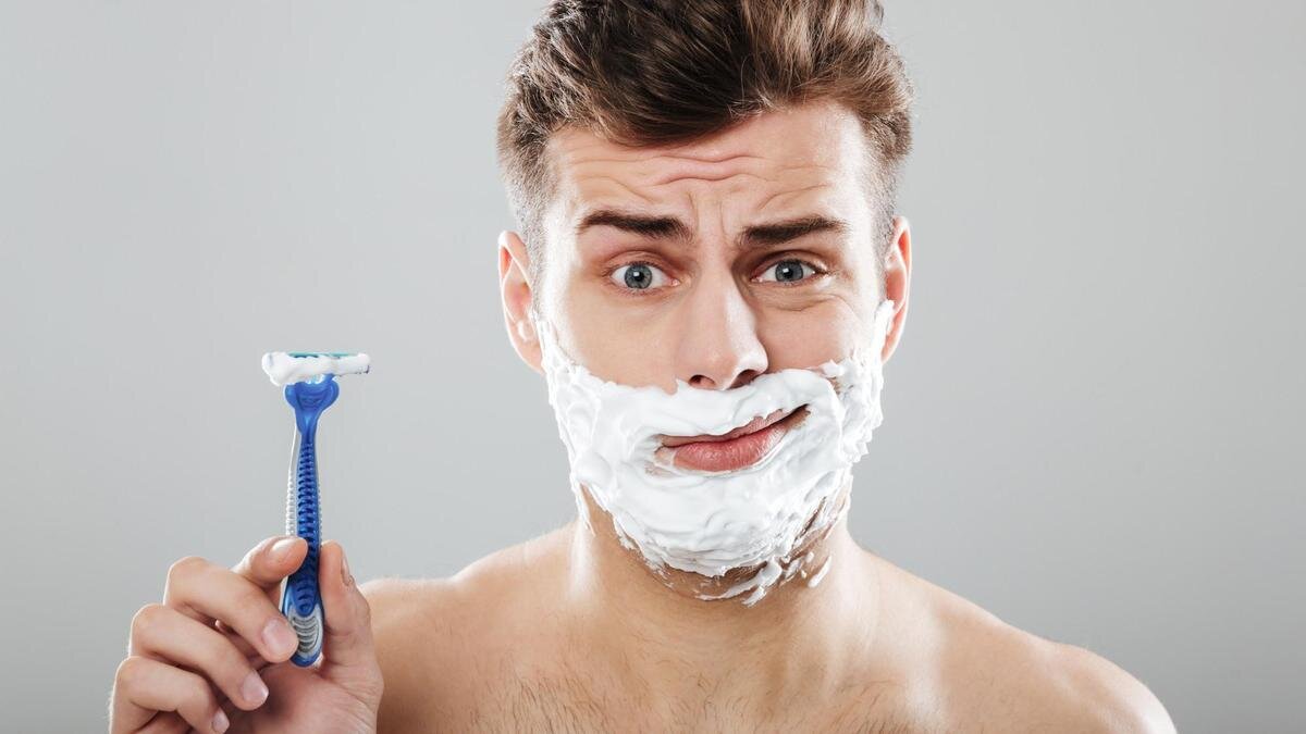    Мужчина с кремом на лице держит в руке бритву:Freepik / drobotdean