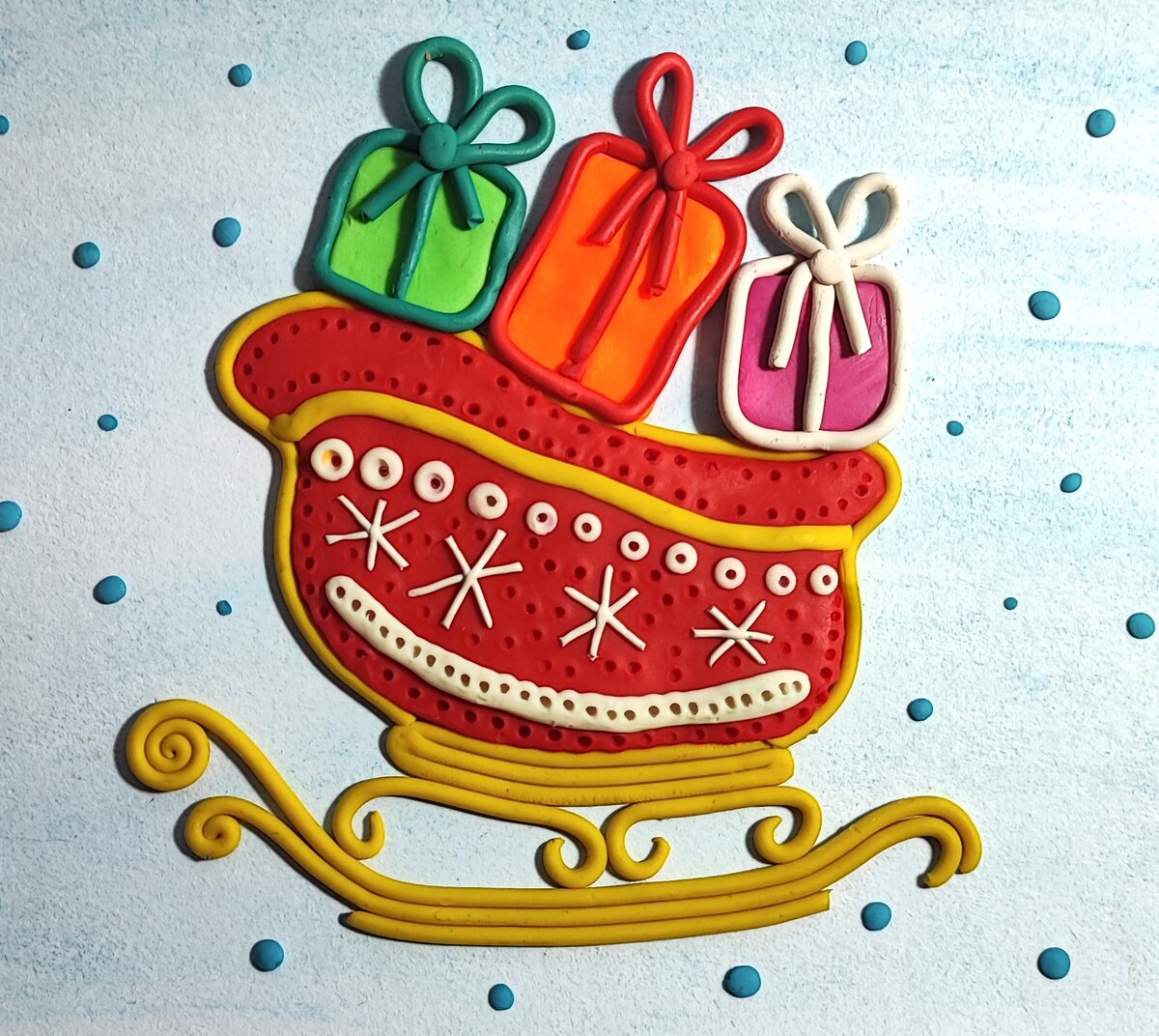 Готовый вариант аппликации из пластилина на картоне Сани Деда Мороза с подарками.