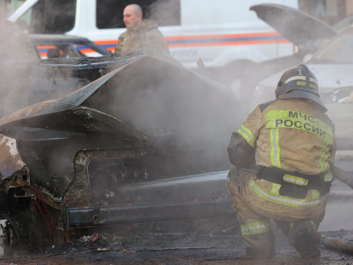    Сотрудник МЧС тушит автомобиль, загоревшийся ранее вследствие удара украинских войск по центру Белгорода© РИА Новости / Антон Вергун