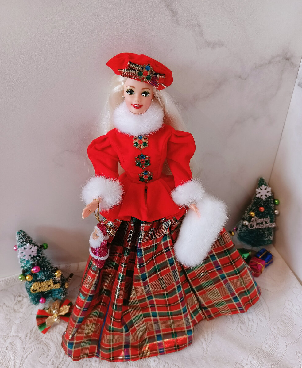 Вот одна из них, на фоне ёлочек, с игрушечным Санта Клаусом в ручке куклы, с её оригинальной муфтой от Mattel