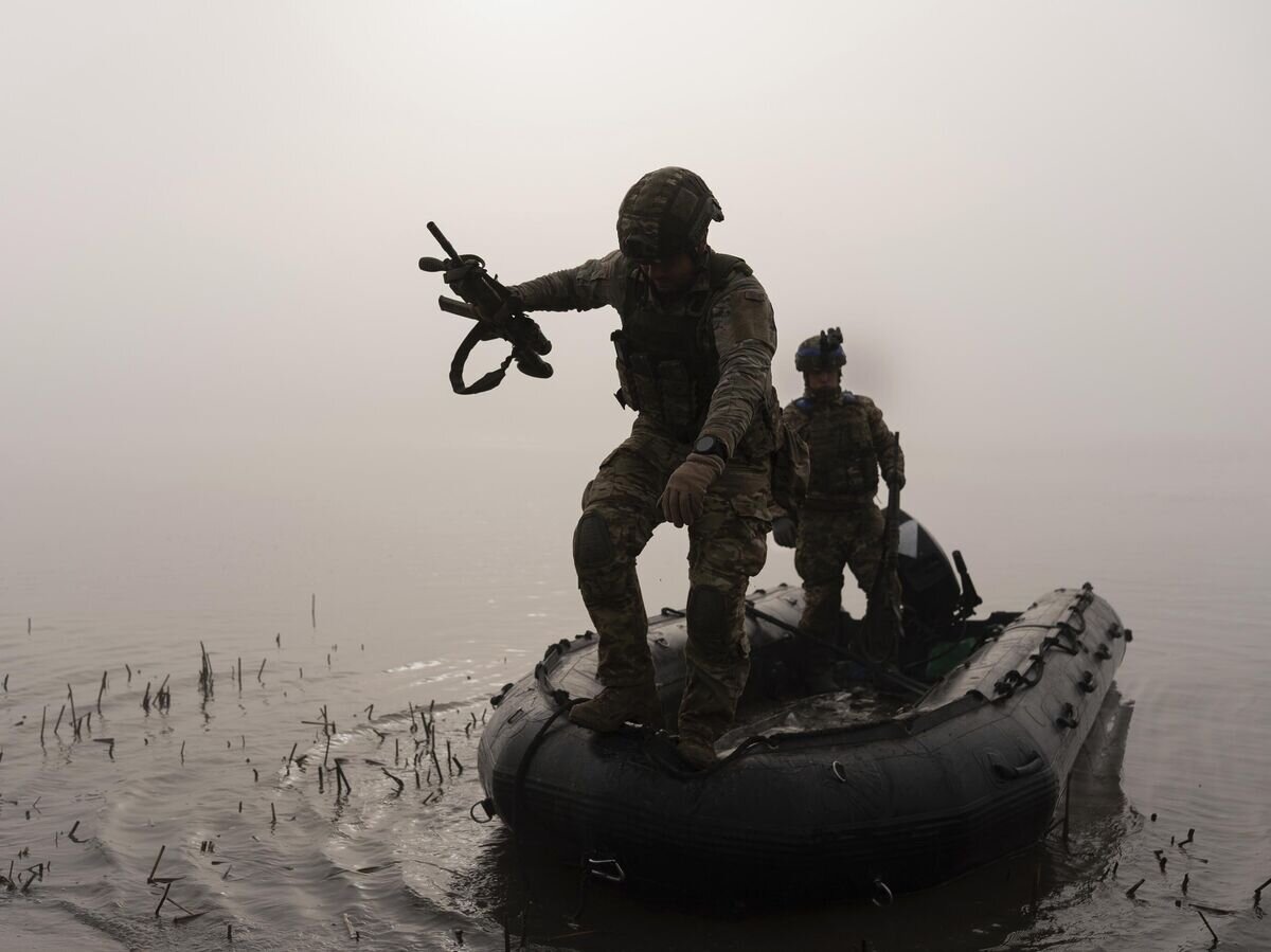    Украинский военнослужащий выпрыгивает из лодки на берег Днепра под Херсоном© AP Photo / Alex Babenko