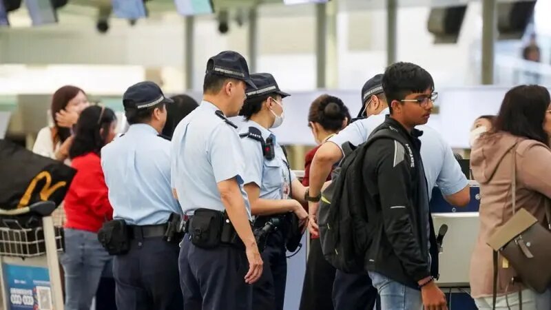 Полиция допрашивает пассажира в зале вылета международного аэропорта Гонконга 5 апреля 2023 года. (Adrain Yu/The Epoch Times)