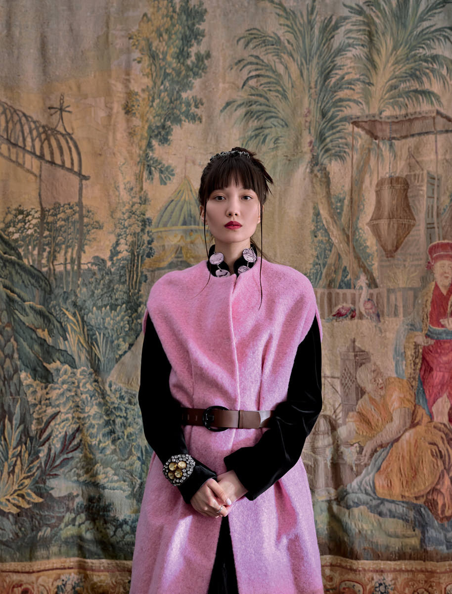 Этот образ вдохновлен легким кино «Безумно богатые азиаты», события которого разворачиваются в одном из самых роскошных и технологичных городов мира — Сингапуре, и лирической героиней знаменитого танго «Магнолия» Александра Вертинского. Модель позирует на фоне подлинной французской шпалеры XVIII века, вдохновленной композициями с китайскими сюжетами, написанными Франсуа Буше для Королевской гобеленовой мануфактуры Бове между 1743 и 1775 годами. Работа украшала один из дворцов Людовика XV, поэтому ее даже касалась рука французского монарха. Гобелен из коллекции Декораторского ателье Марка Патлиса.
На модели: розовое пальто без рукавов Marni, черное бархатное пальто под ним винтажное, браслет Banana Republic.