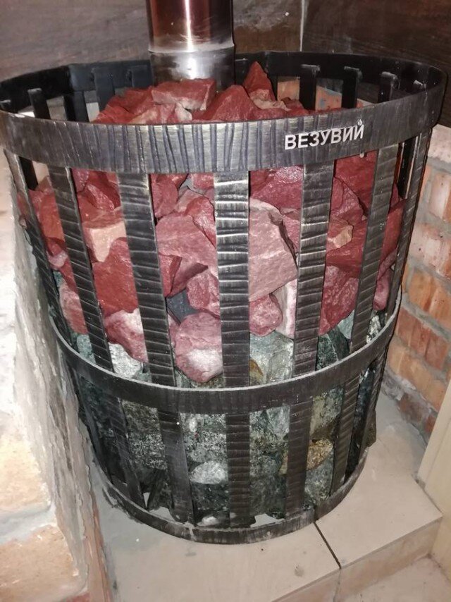 Крупный камень разных пород в сетке банной печи