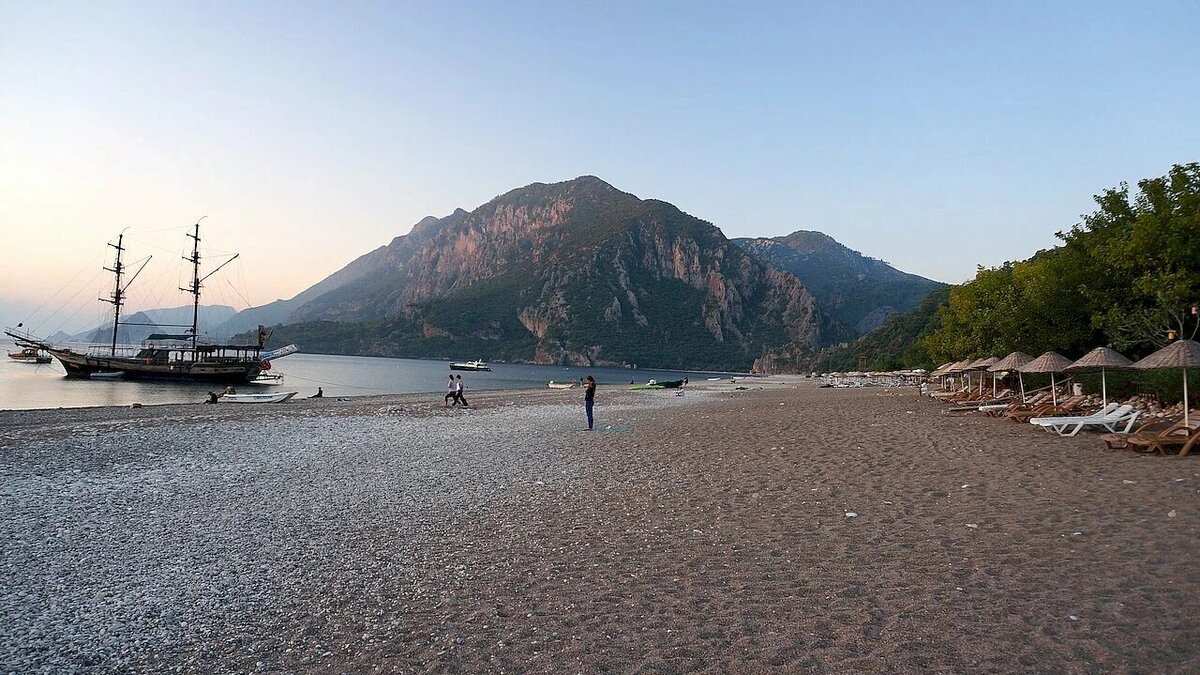 Рядом с пляжем находится гора Янарташ, из которой периодически извергаются языки пламени — это самовозгорание метана, одна из местных достопримечательностей. Вход на гору открыт круглосуточно и стоит, в зависимости от сезона, от 20 до 40 лир, но особенно эффектно здесь в сумерках. Фото: Алекс Ю. / Яндекс Карты