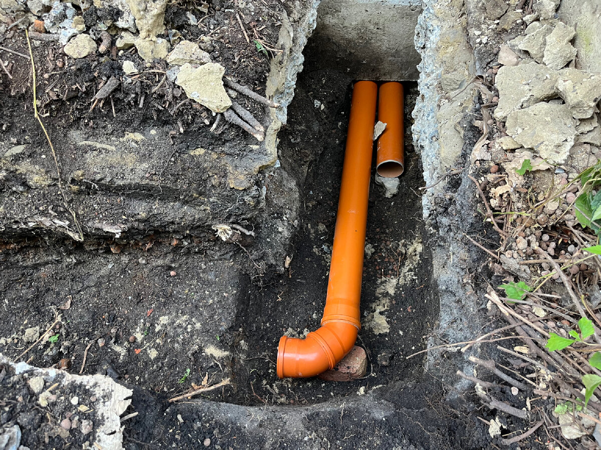 Водопроводная труба-гильза и канализационная труба выходят из под дома.