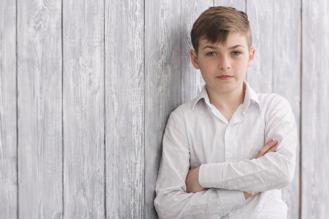    Подросток стоит, опираясь на стену:Freepik