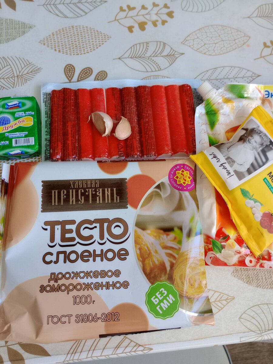 Продукты: 1.	Слоеное дрожжевое тесто – 1 пачка.
2.	Яйцо – 3 штуки.
3.	Крабовые палочки – 1 пачка.
4.	Сыр плавленый – 1 штука.
5.	Чеснок – 1 зубчик.
6.	Майонез – 2 столовые ложки.
7.	Зелень – по вкусу.
8.	Мини моцарелла – 1 упаковка (вместо моцареллы можно использовать перепелиные яйца).
