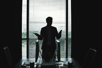    Темный силуэт бизнесмена, стоя у окна офиса и держа планшет и смартфон ©pressfoto Freepik