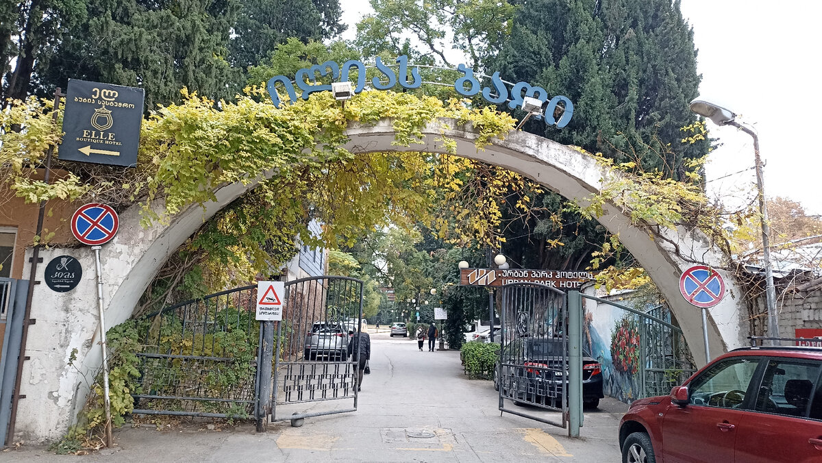 Фото входа в парк. Вход в парк свободный и оригинально оформлен большой оплетенной вьющимся растением аркой.