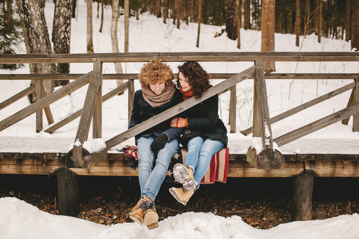 фото источник ID 50573984© Katsiaryna Pakhomava Dreamstime.com   https://www.dreamstime.com/stock-photo-young-couple-sitting-wooden-bridge-winter-forest-curly-hair-hipster-image50573984