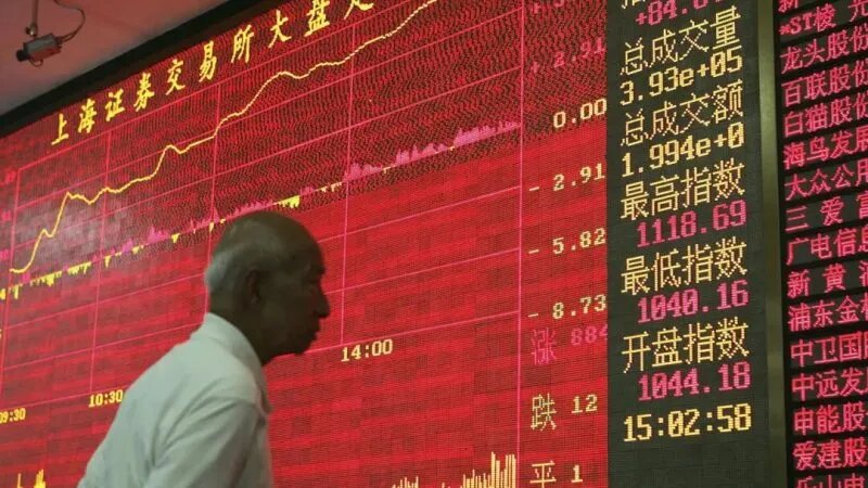 Инвестор смотрит на электронный индикатор фондового индекса в компании по ценным бумагам в Шанхае, 8 июня 2005 года. (China Photos/Getty Images)