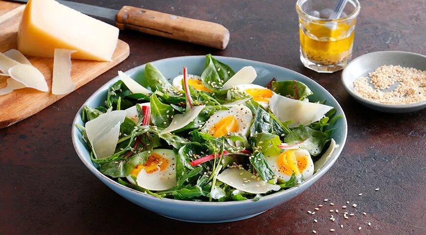 Зеленые салатные листья с сыром, яйцами и кунжутной заправкой